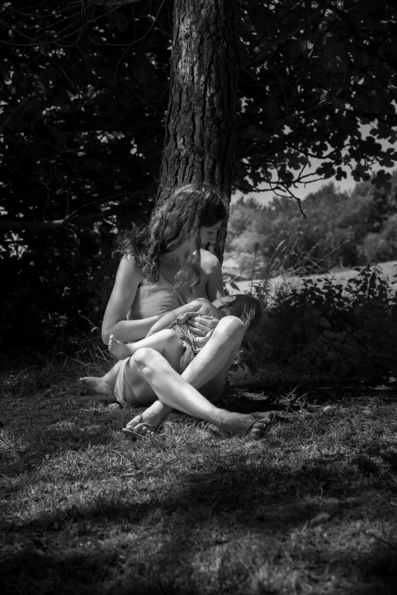Portrait mère-fille en noir et blanc, en extérieur près d’un arbre.