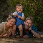 Portrait allongé d’une famille en forêt au bord de l’eau.