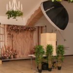 Photobooth professionnel en intérieur à Perpignan avec éclairage studio, fond décoratif fleuri et accessoires végétaux, idéal pour événements et mariages.