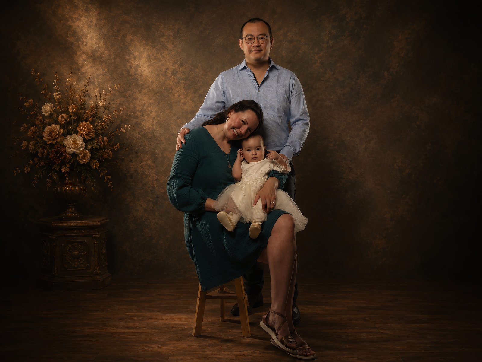 Portrait de famille réalisé en studio à Ille-sur-Têt avec des parents et leur bébé dans une ambiance fine art chaleureuse.
