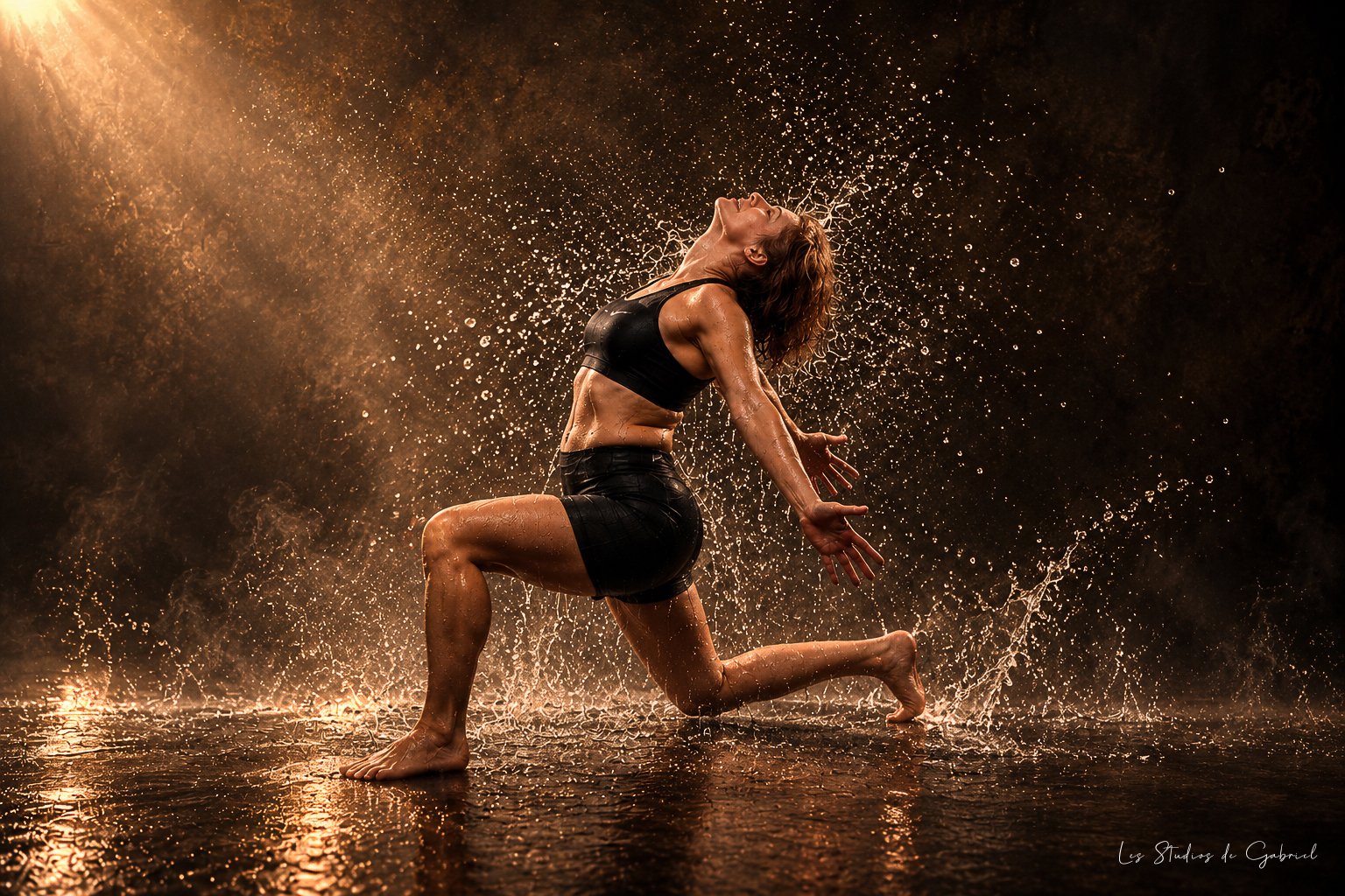 Portrait sportif Fine Art d’une femme en fente, entourée d’éclaboussures d’eau et éclairée par une lumière dorée.